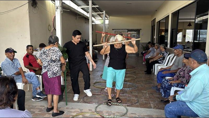 Una adulta mayor camina entre aros guiada por el fisioterapeuta