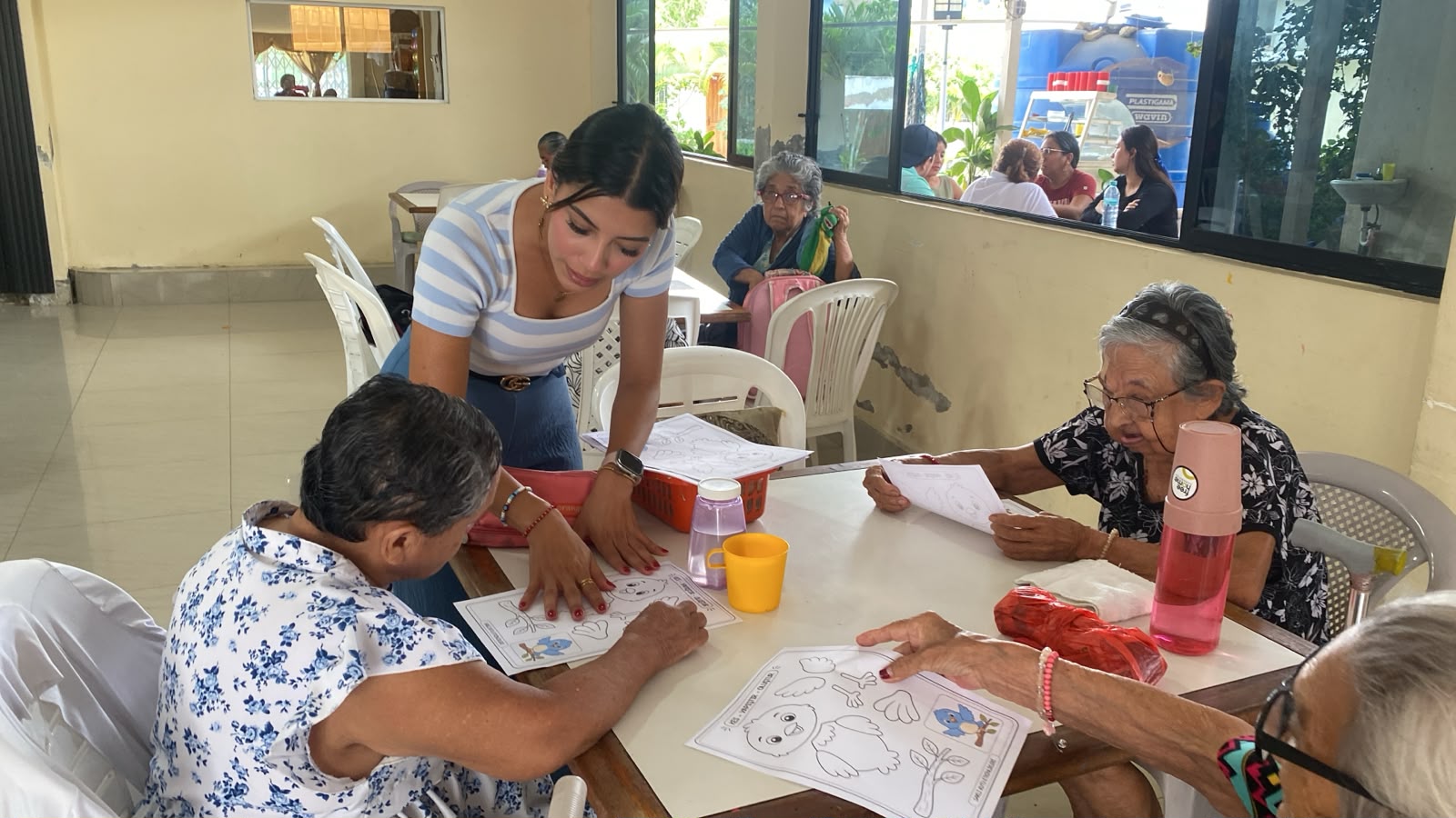 Una técnica guía a tres adultas mayores en una actividad de dibujo